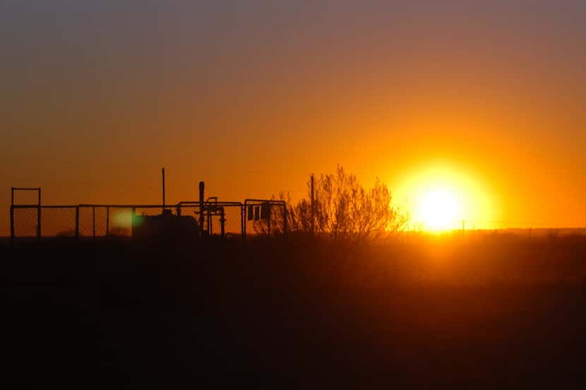 The sun sets behind Devon Energy's East Ponder Well No. 4, Thursday, January 5, 2012, in...