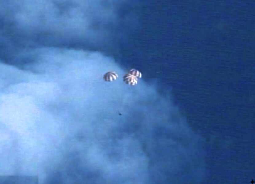The Orion spacecraft descends before splashing down in the Pacific Ocean following a...