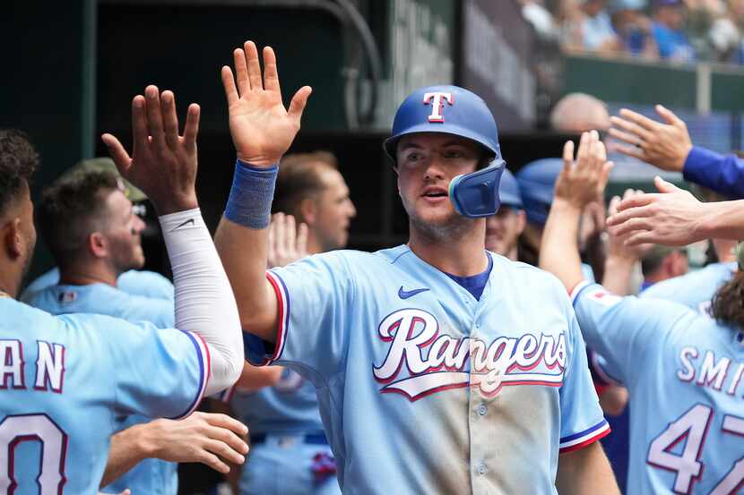 Texas Rangers third baseman Josh Jung celebrates in the dugout after scoring on a...