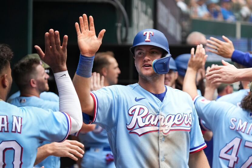 Texas Rangers third baseman Josh Jung celebrates in the dugout after scoring on a...