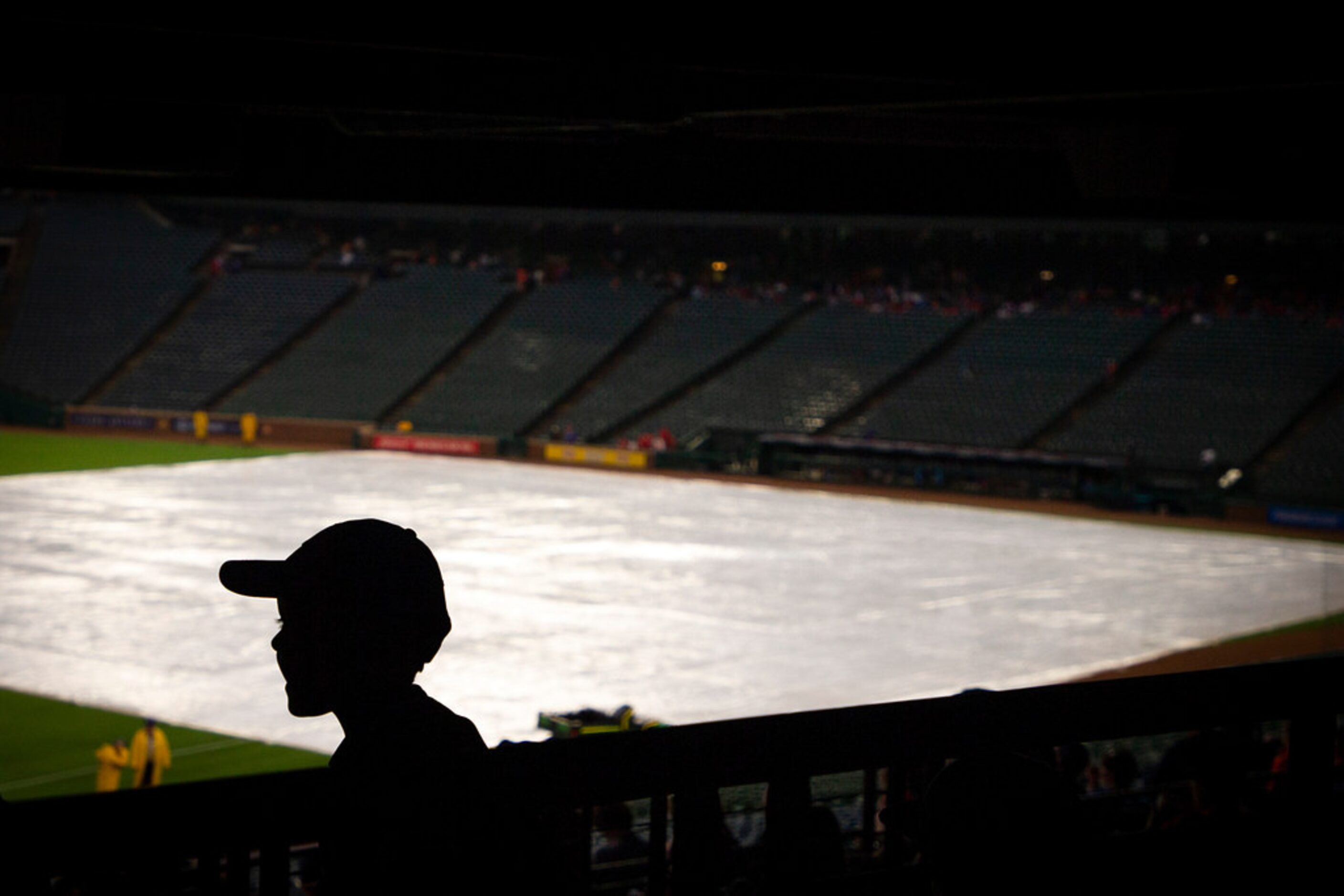 Fans take cover during a rain delay before a baseball game between the Texas Rangers and the...