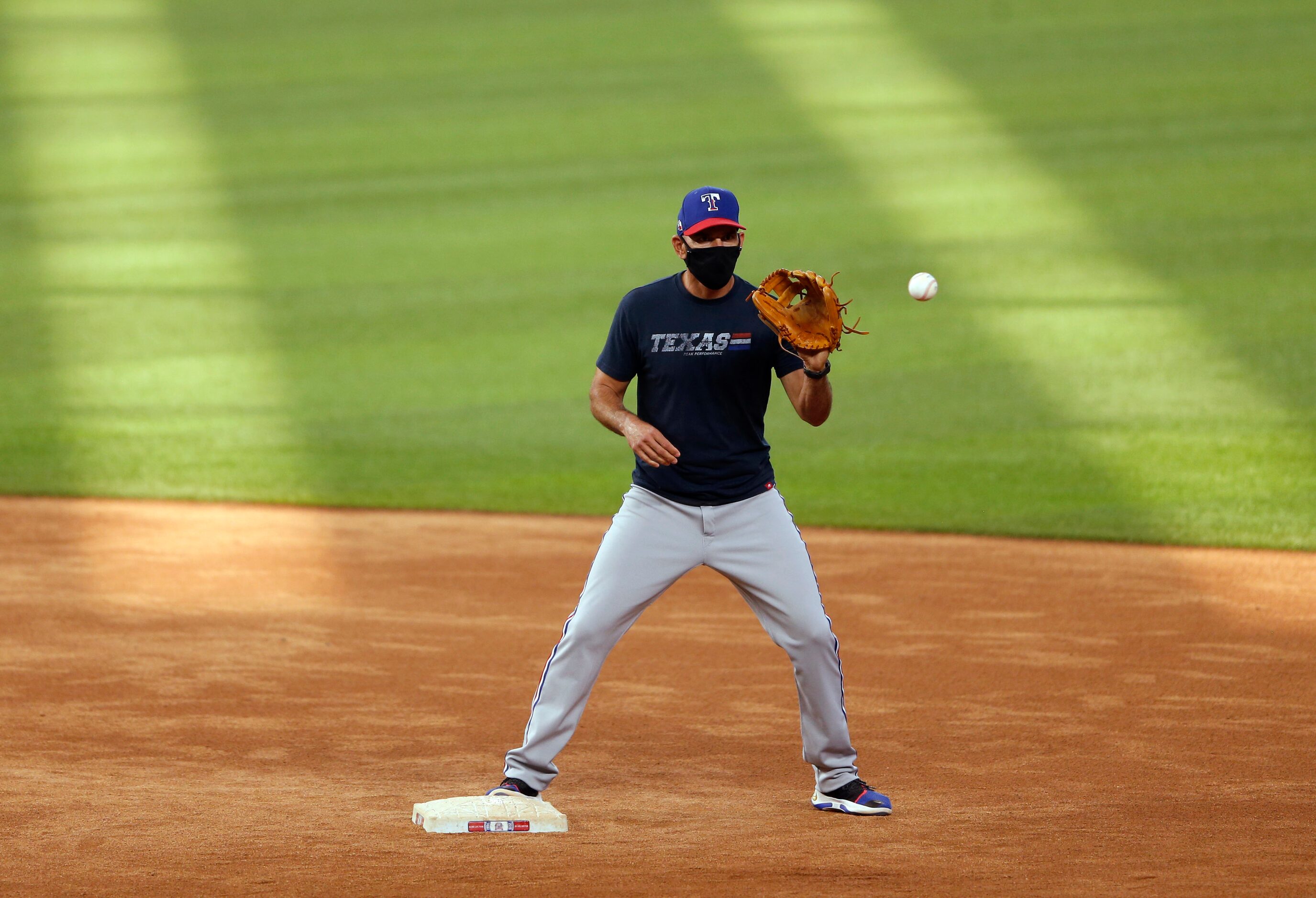 Texas Rangers manager Chris Woodward prepares to catch the ball during batting practice at...