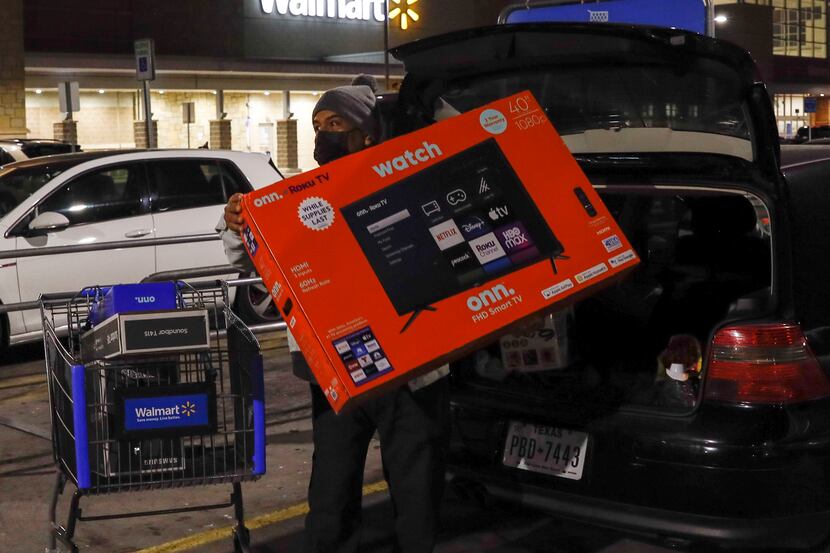 Louis Garcia, loads a 40-inch TV into the back of his car just before 6 a.m. during Black...