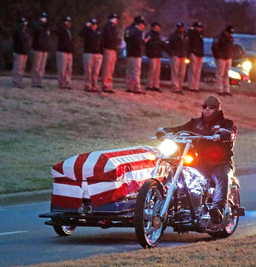 Officers solemnly salute as a motorcycle carries the body of Richardson police officer David...