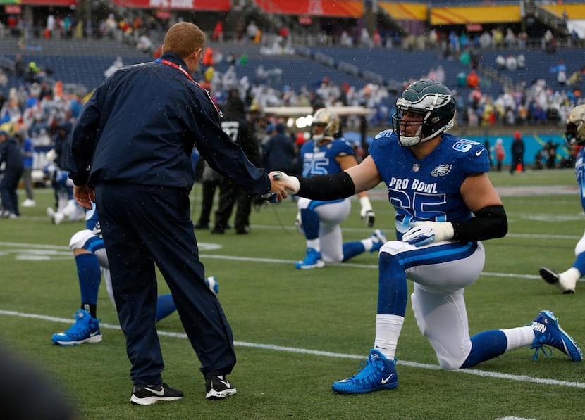 NFC head coach Jason Garrett, of the Dallas Cowboys, shakes hands with tackle Lane Johnson...