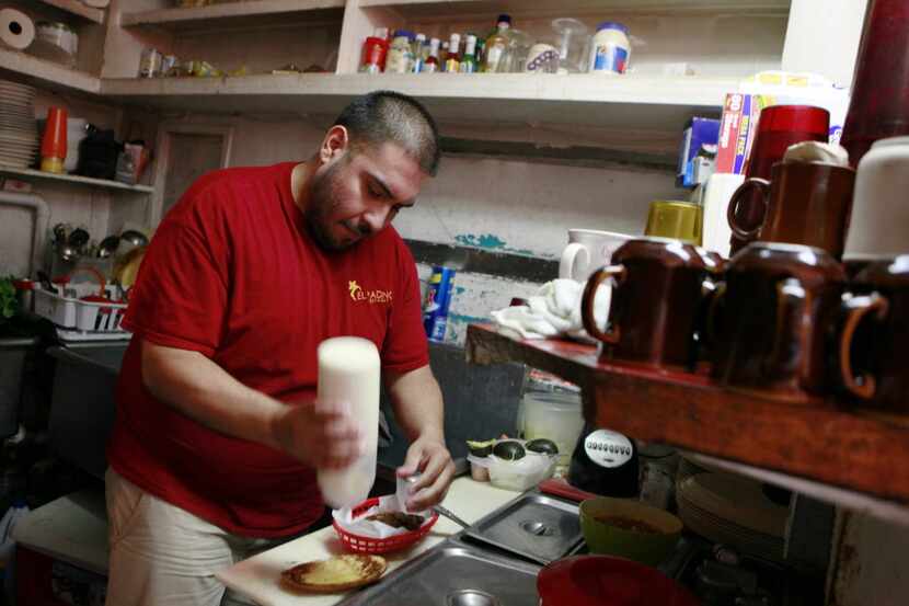 Co-owner of El Padrino restaurant Juan Contreras Jr., prepares a sandwich for a customer...
