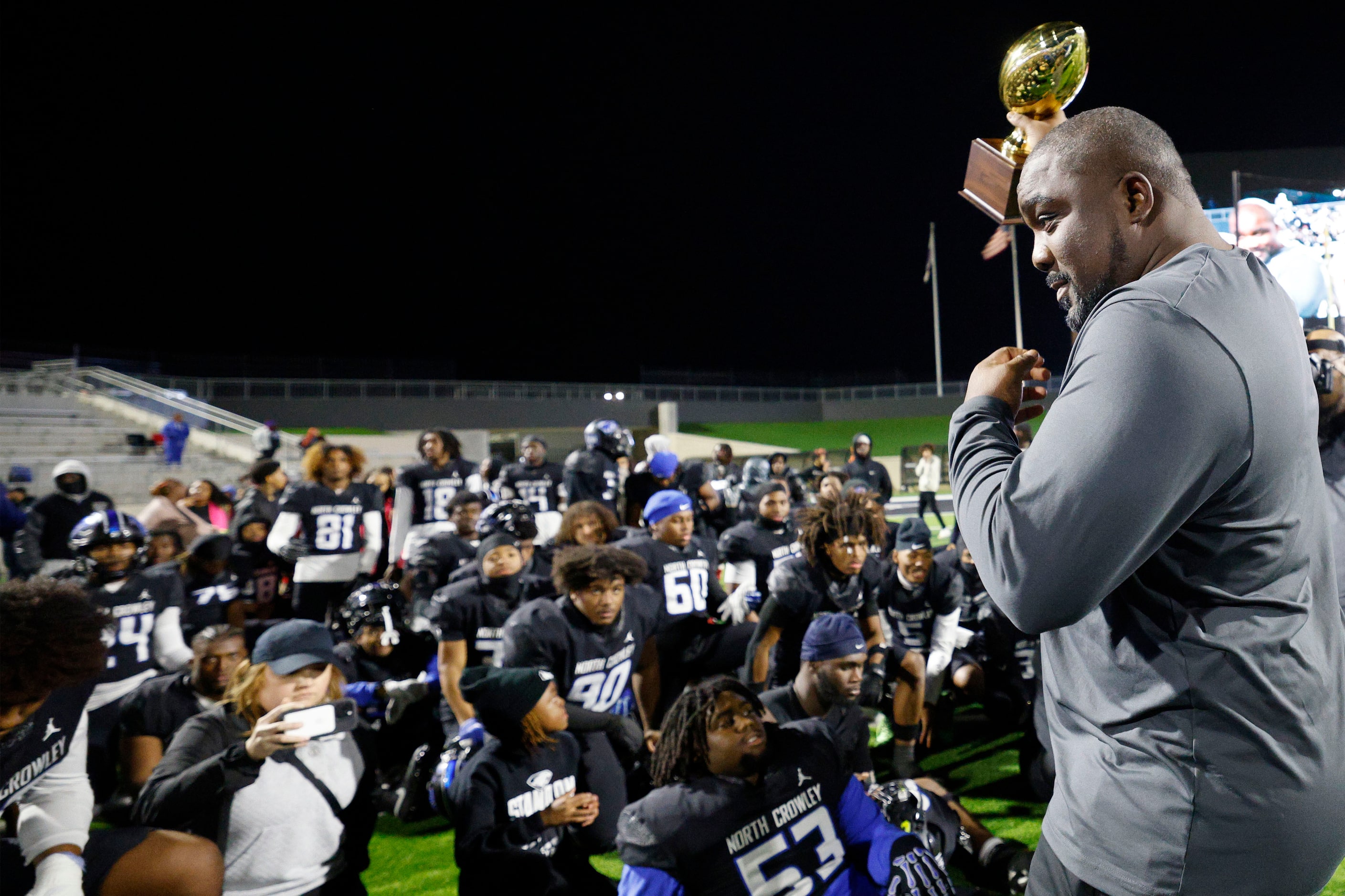 North Crowley’s head coach Ray Gates holds up a trophy after their 72-14 victory against...