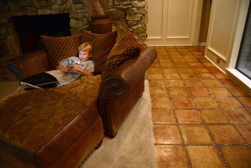 Matt Rawlston, 10, checks his phone after playing outside his home in Bent Tree North.