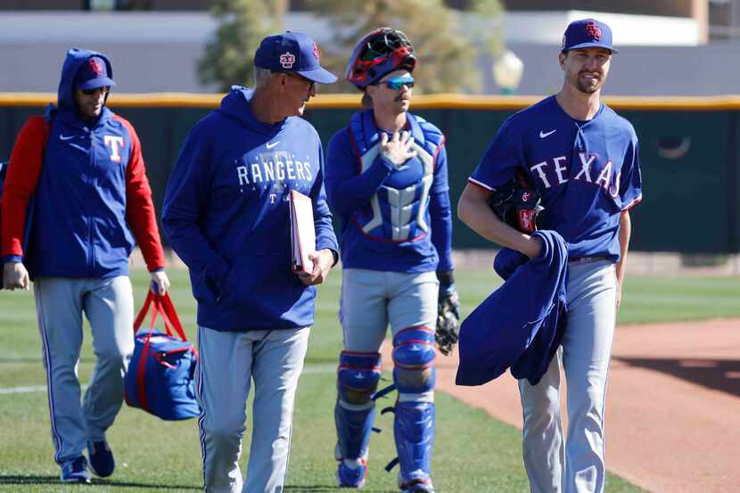 Texas Rangers pitching coach Mike Maddux, front left, talks to pitcher Jacob deGrom, right,...