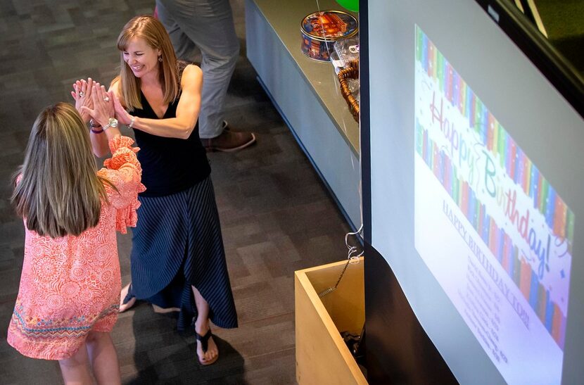 Lindsay Hendricks (facing) high fives a co-worker during a party celebrating the month's...