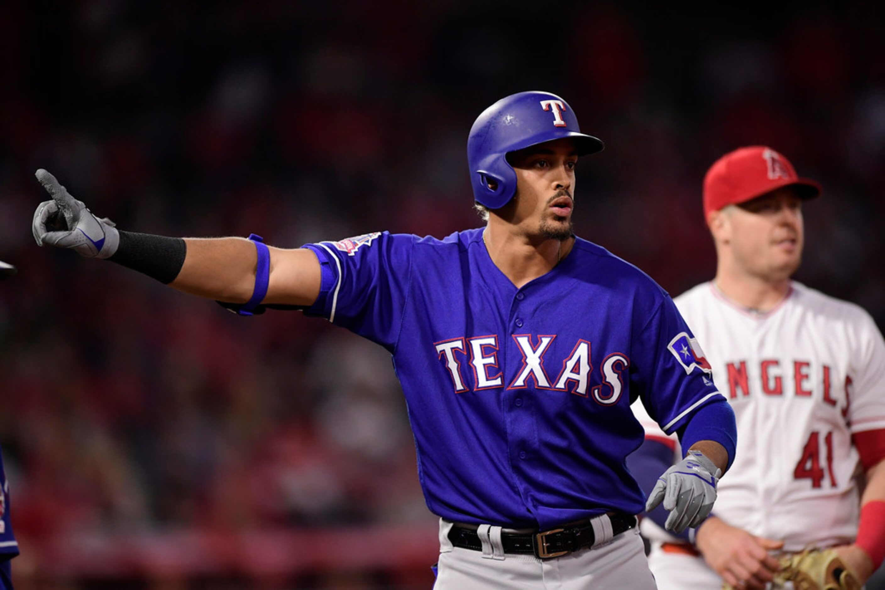 Texas Rangers' Ronald Guzman, left, gestures as he waits, along with Los Angeles Angels...