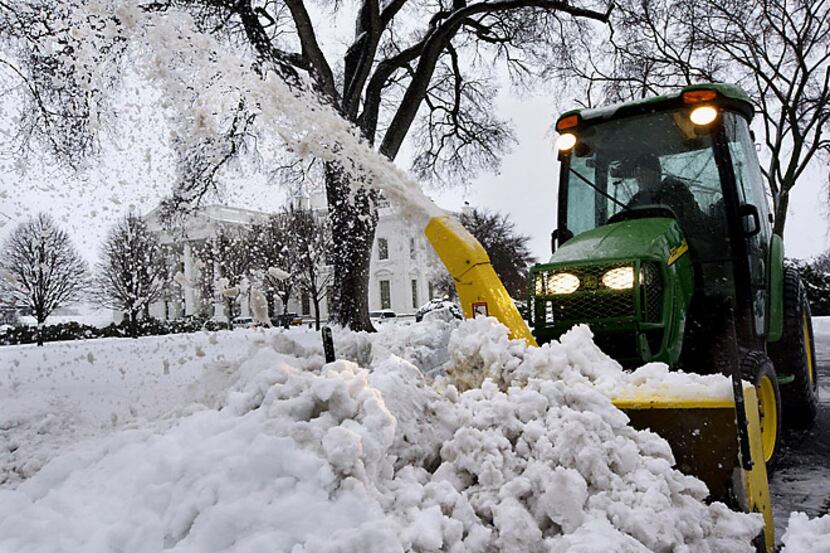 A combination snowplow and blower clears the White House driveway Thursday morning in...