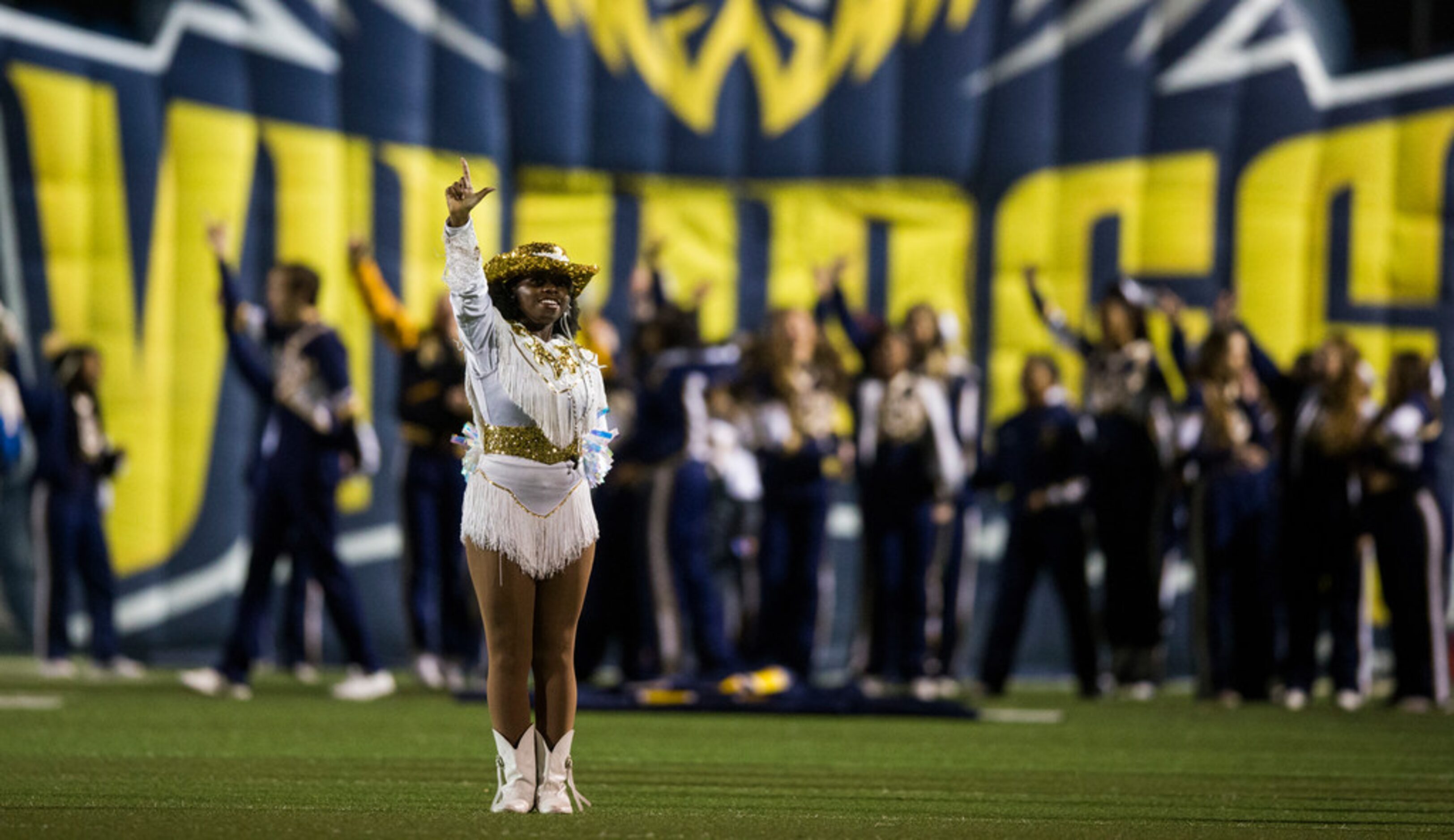 An Arlington Lamar dance team member holds p an L for Lamar as the band plays the school...