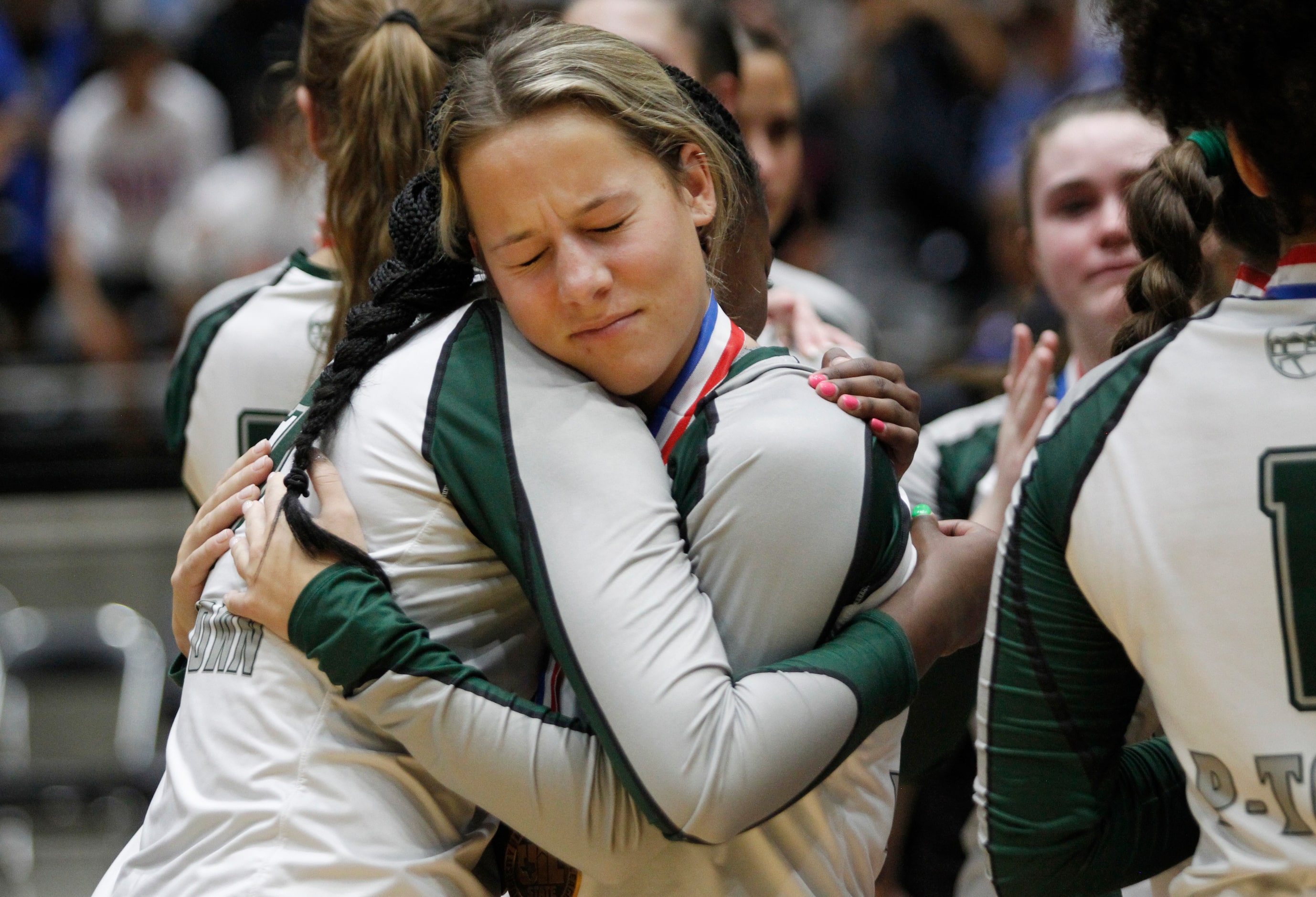 Prosper senior Taylor Gardner (4), center facing camera, shares a hug with a teammate...