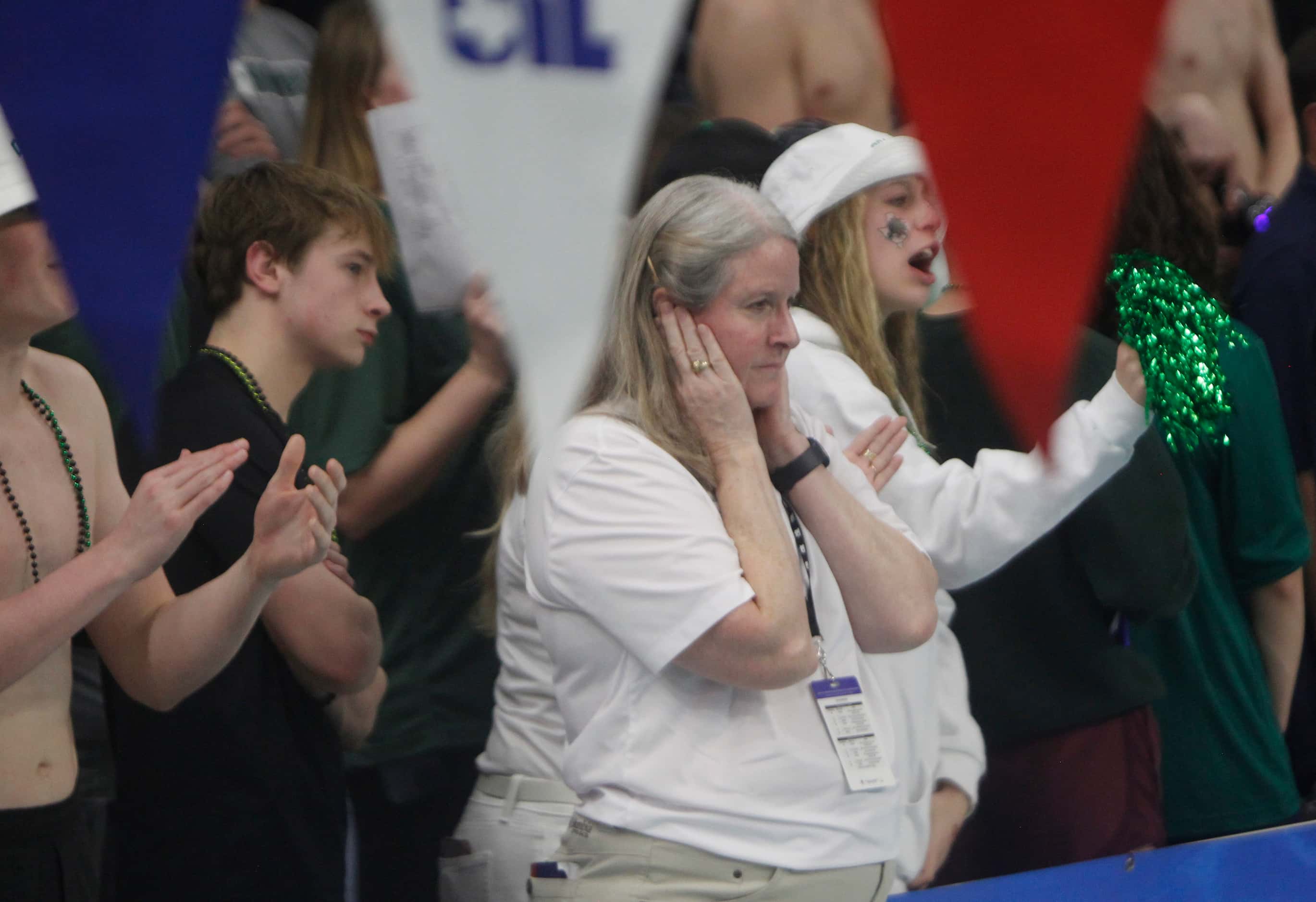 A UIL official protects her hearing as a sold out crowd cheers on swimmers and divers...