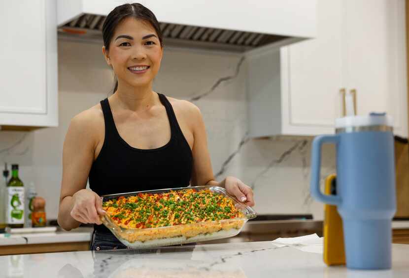 Alissa Nguyen smiles at the camera while holding a tray of food.