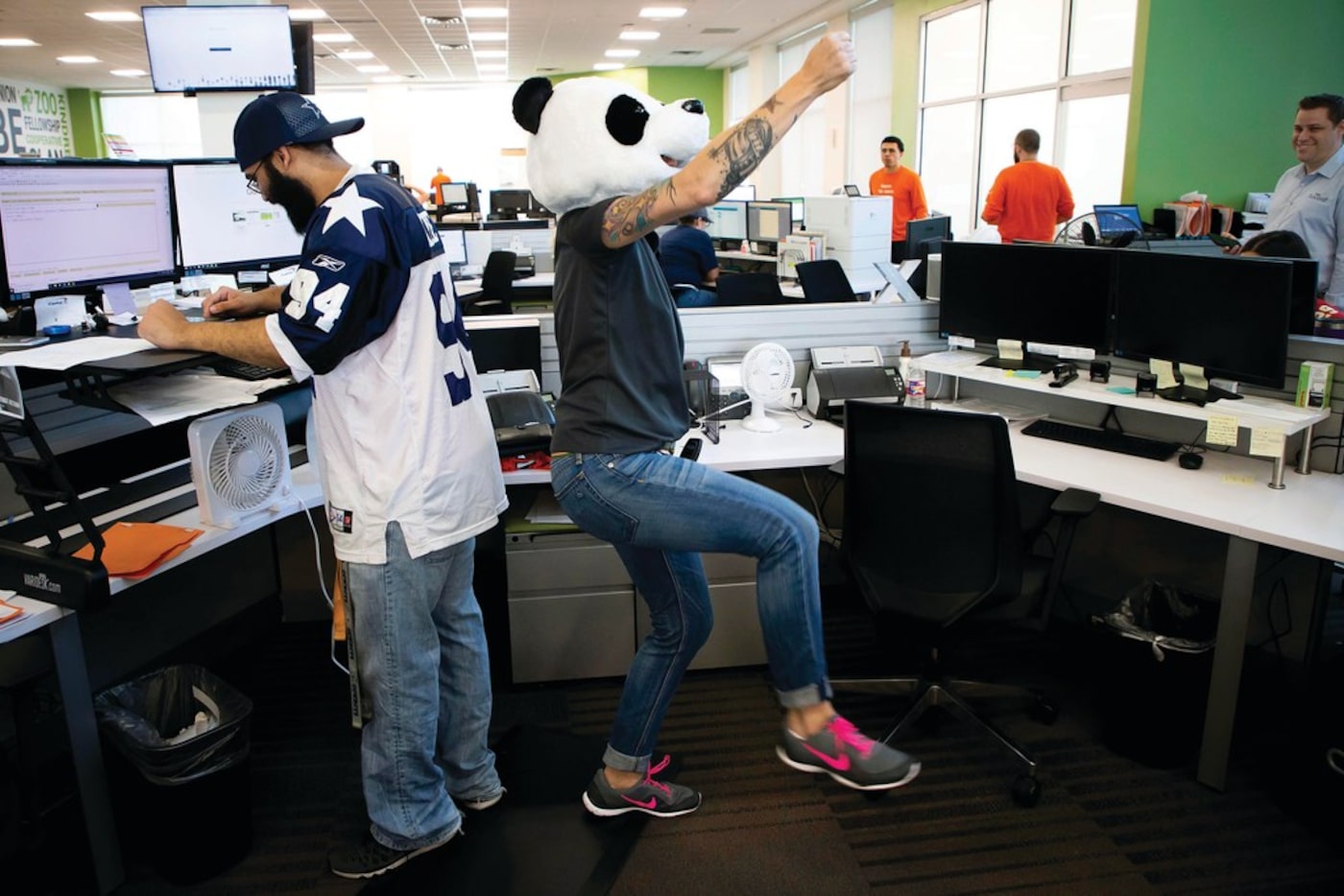 Wearing a panda head, Brandi Beakley dances near the desk of Cameron Ratcliff at Driversselect.