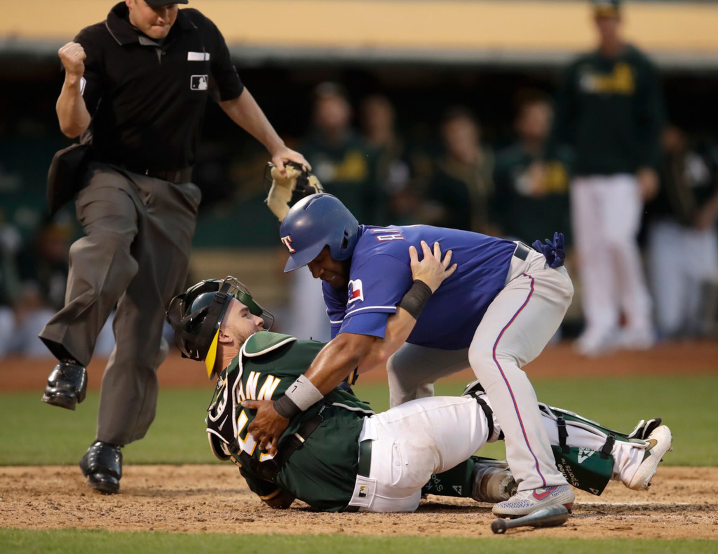 Texas Rangers' Elvis Andrus, top, assists Oakland Athletics catcher Chris Herrmann to his...