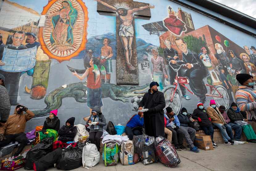 Migrantes comen y esperan ayuda, acampados en una calle del centro de El Paso, Texas, 18 de...