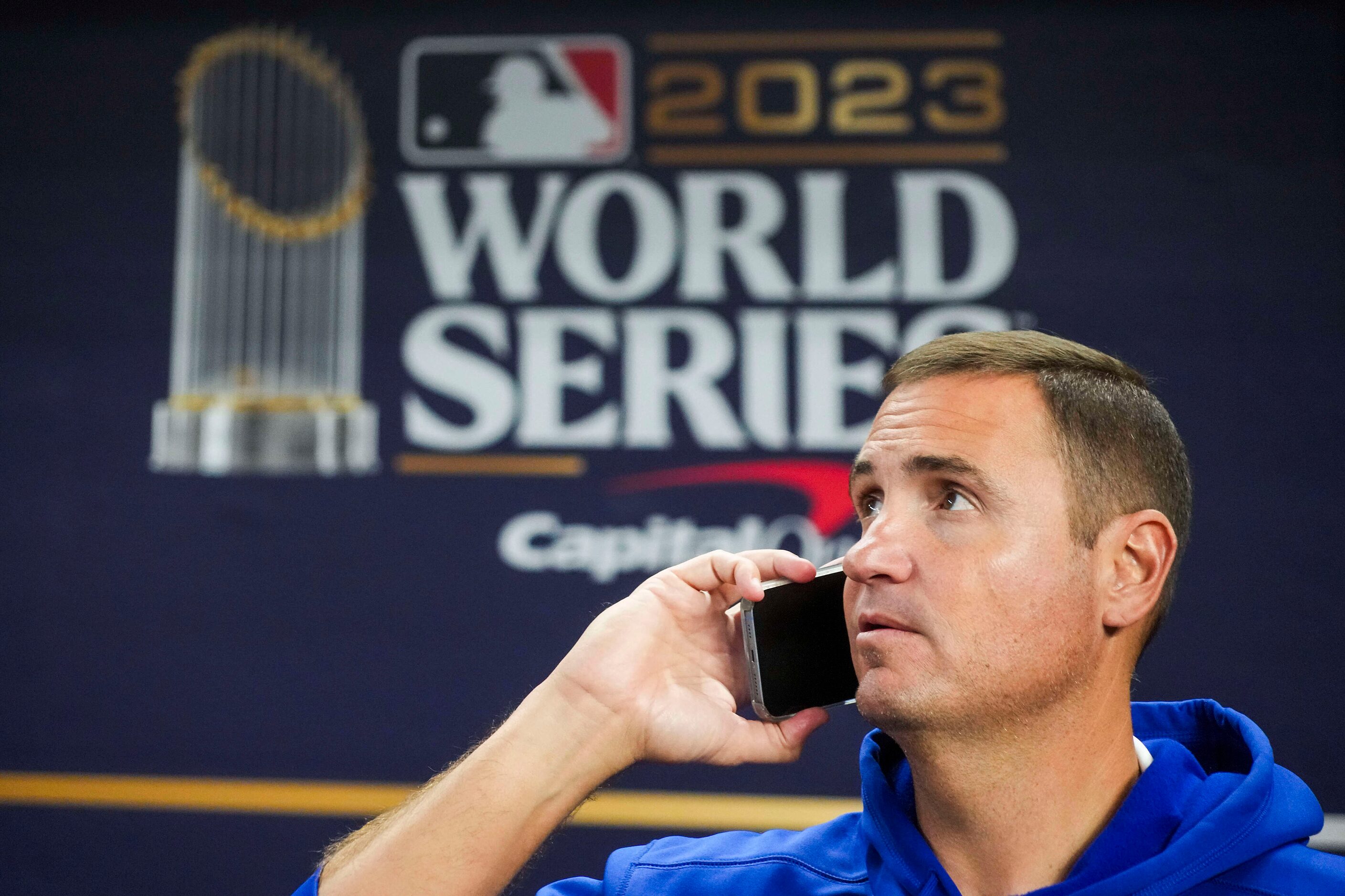 Texas Rangers general manager Chris Young looks out from the dugout as he talks on the phone...