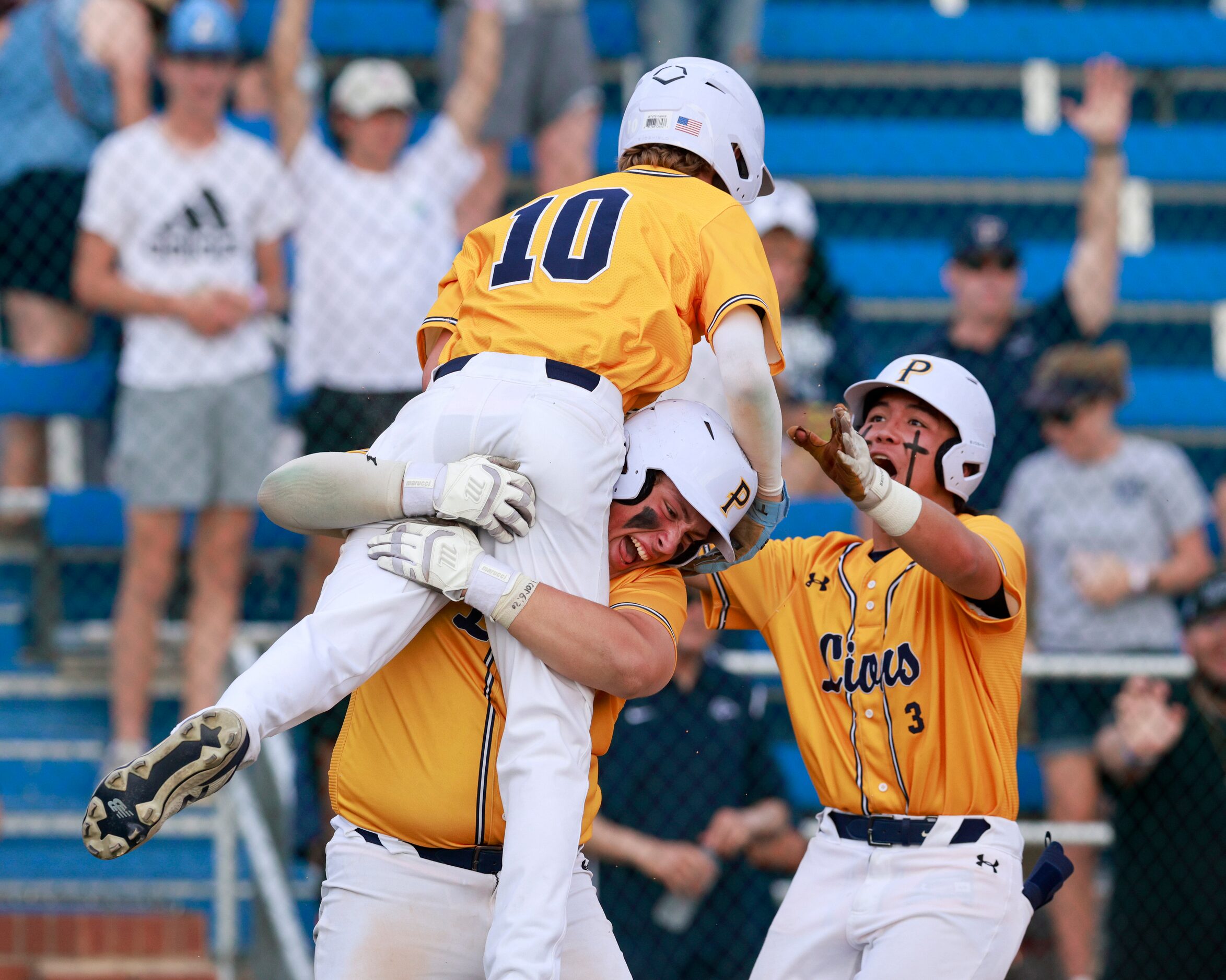 Plano Prestonwood designated hitter Dylan Brown (center) lifts infielder Tanner Trout (10)...