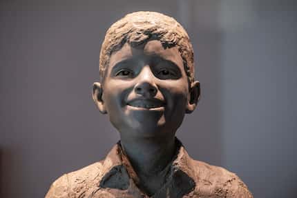 Una estatua de Santos Rodríguez de 6 pies de alto, sonriendo y mirando hacia arriba, con los...