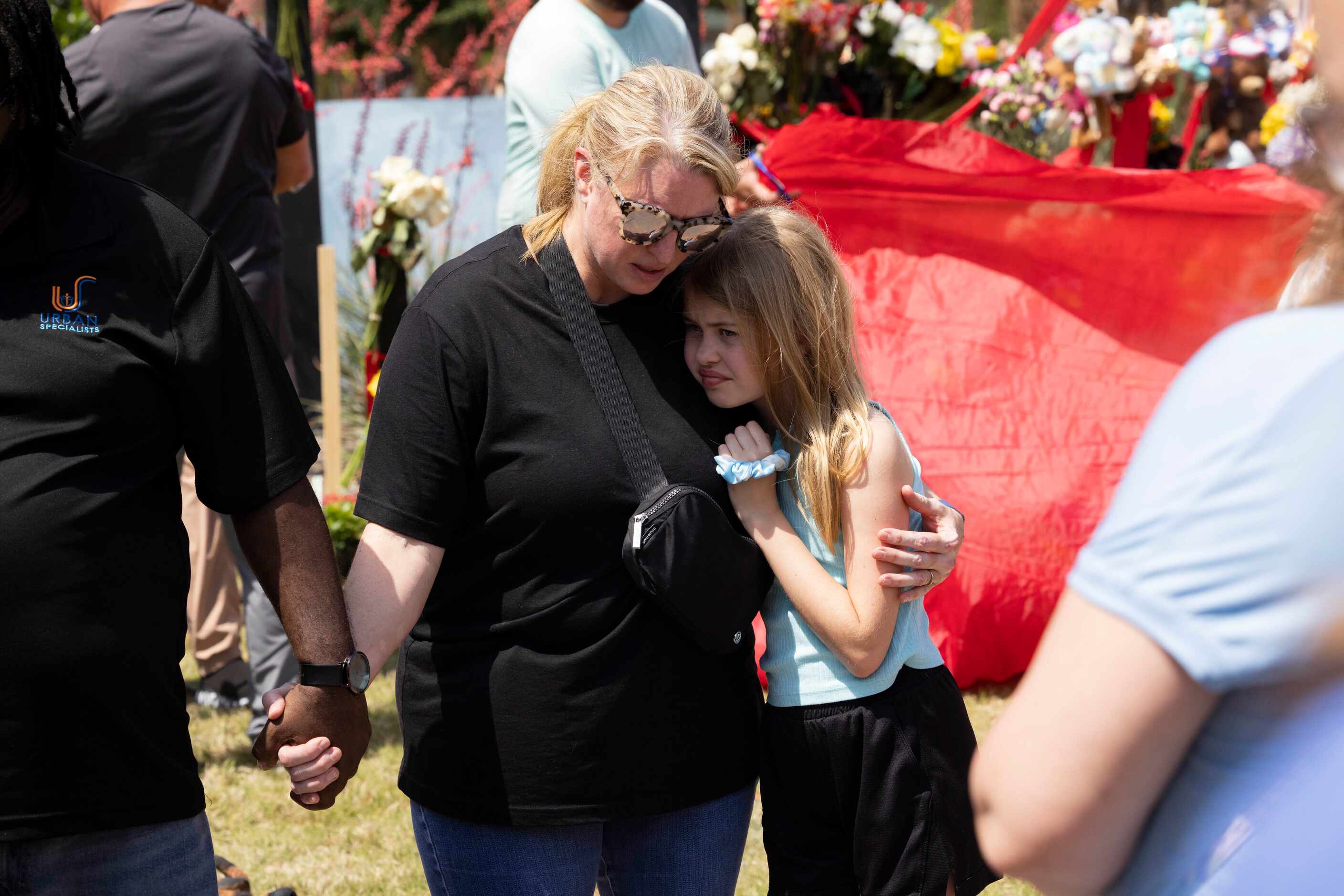 Jessica Himes of Allen holds daughter Harper as they pray at a memorial outside the mall...