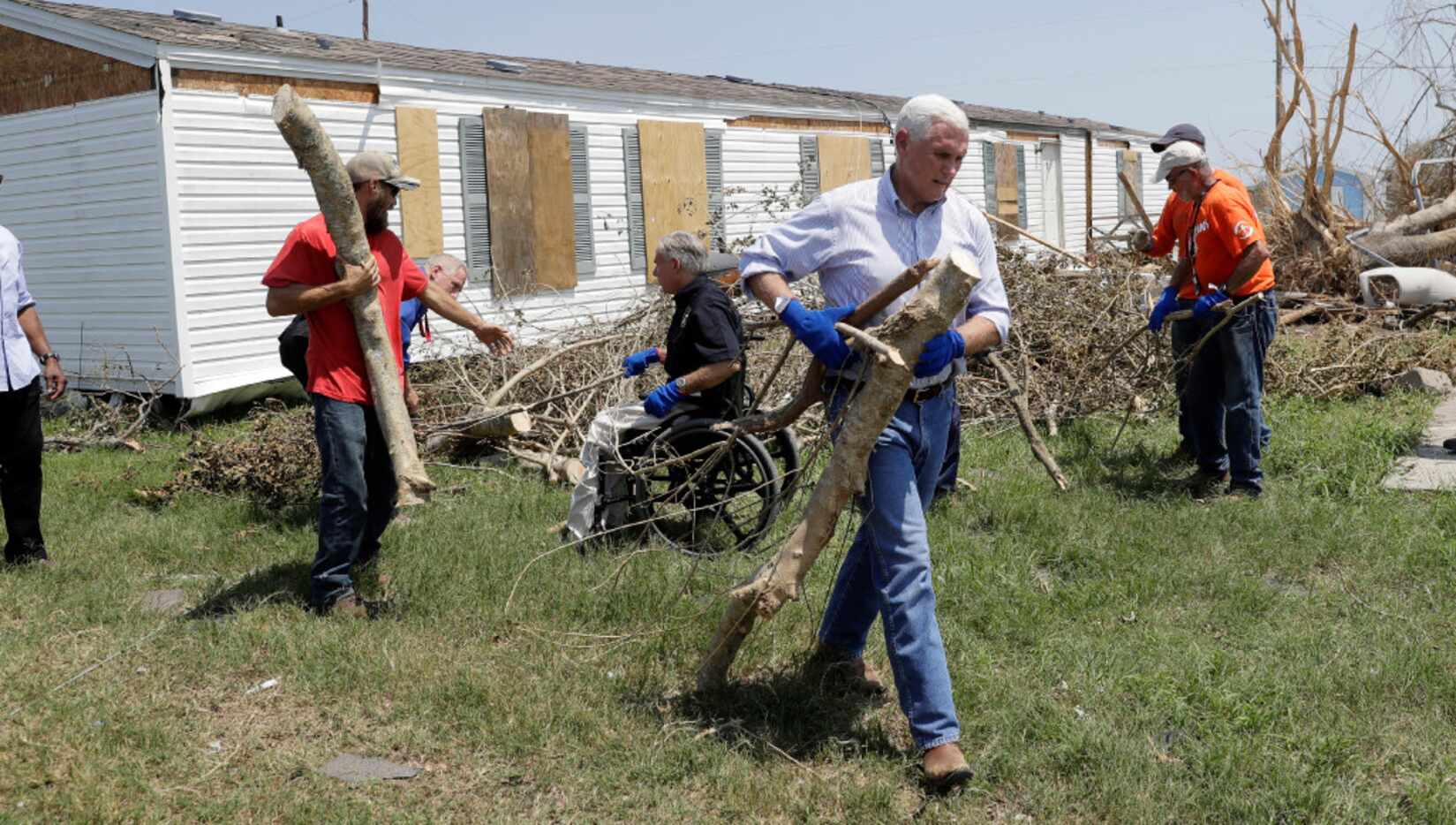 Vice President Mike Pence carries away debris as he and Texas Gov. Greg Abbott (center in...