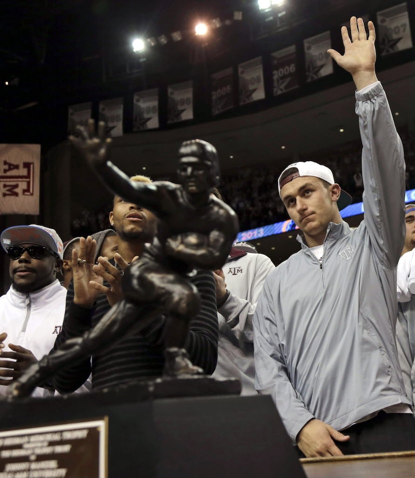 Texas A&M quarterback Johnny Manziel, right, waves to the crowd as he stands behind his...