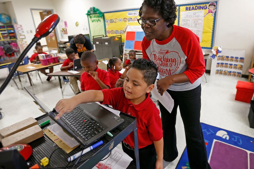 Teacher Vondella Rogers (right) helps kindergarten student Adrian Flores during a coding...