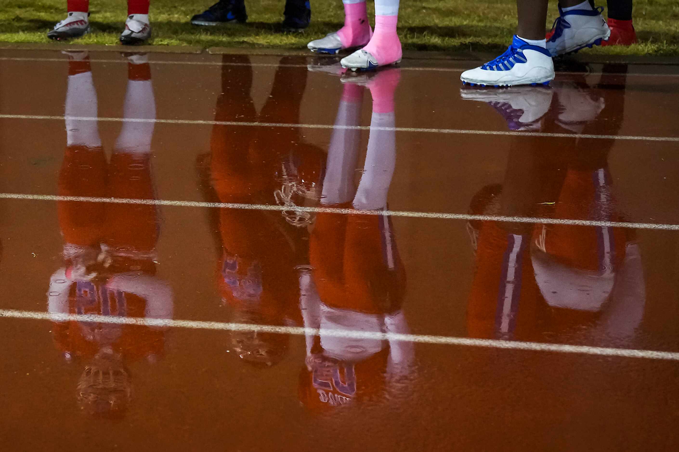 Duncanville players are reflected in puddles on the track before a District 11-6A high...