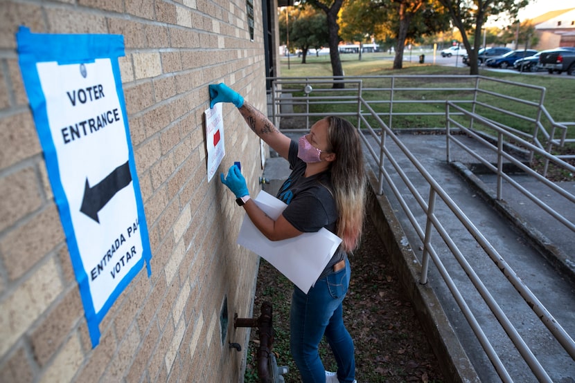 Poll worker Juliana Lee posts entrance signs displaying where to vote outside of the polling...