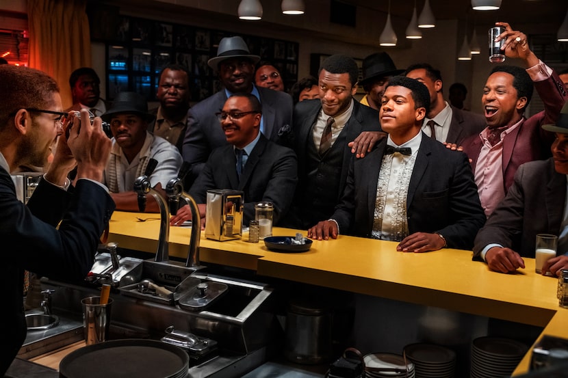 Kingsley Ben-Adir as Malcolm X, far left, takes a photo of Aldis Hodge (standing, center, in...