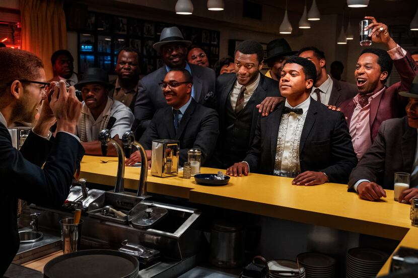 Kingsley Ben-Adir as Malcolm X, far left, takes a photo of Aldis Hodge (standing, center, in...