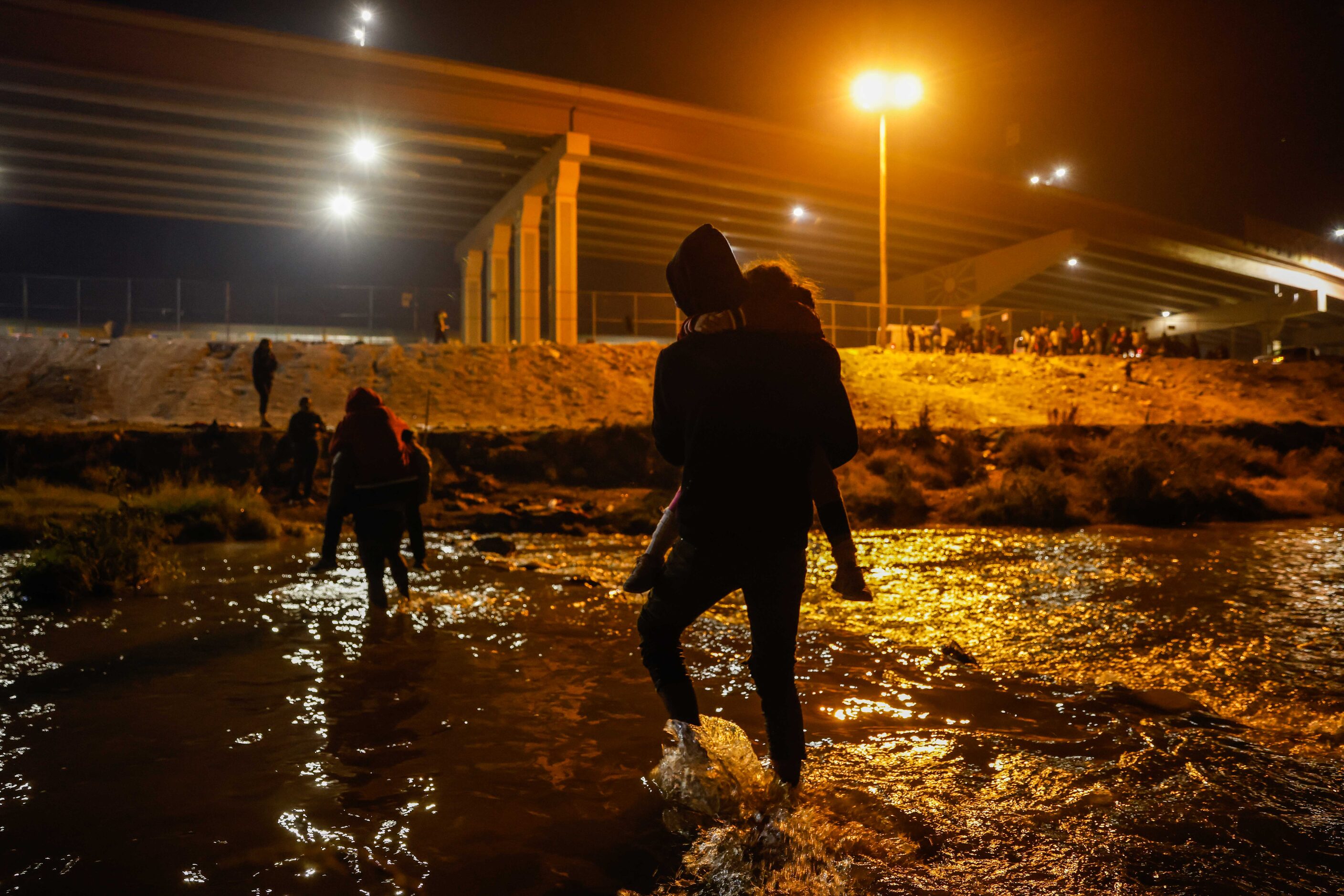 Migrants cross the Rio Grande river and US-Mexico border into El Paso, Texas as seen from...