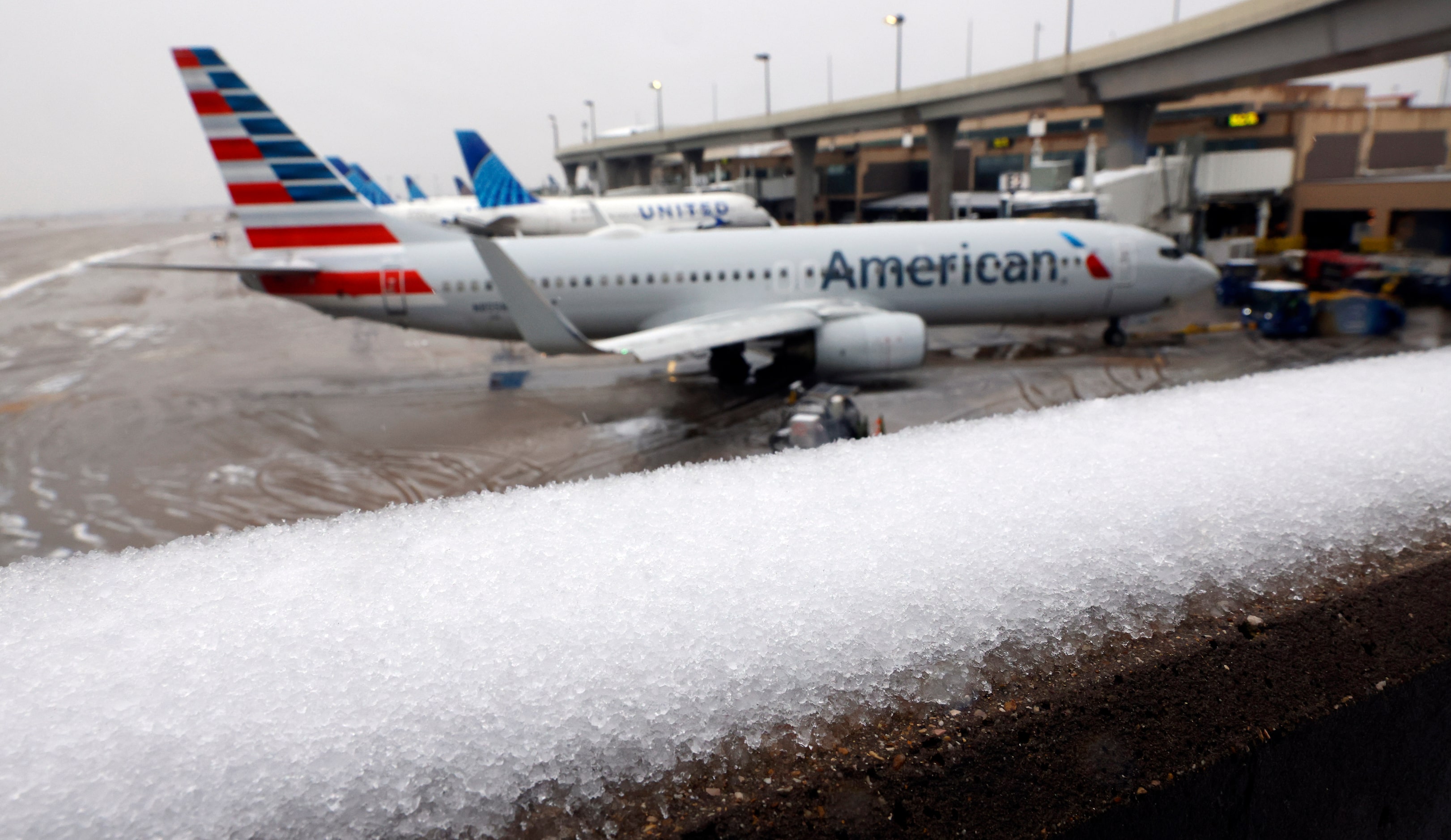 Sleet covers a bridge as an American Airlines jet waits for departure from DFW Airport’s...