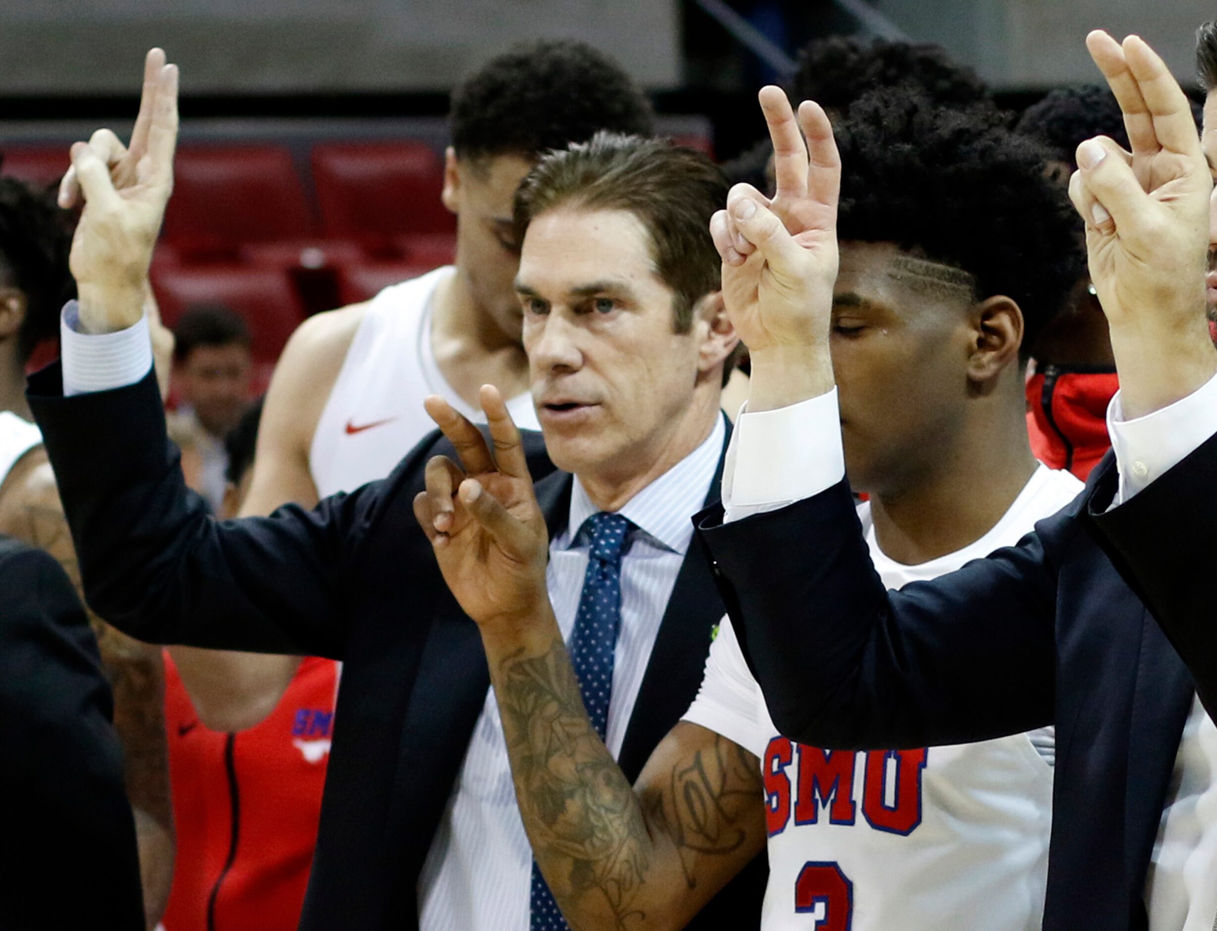 SMU head coach Tim Jankovich pauses with players and coaches for the playing of the school...