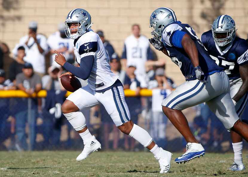 Dallas Cowboys quarterback Dak Prescott, left, scrambles during a scrimmage at the training...
