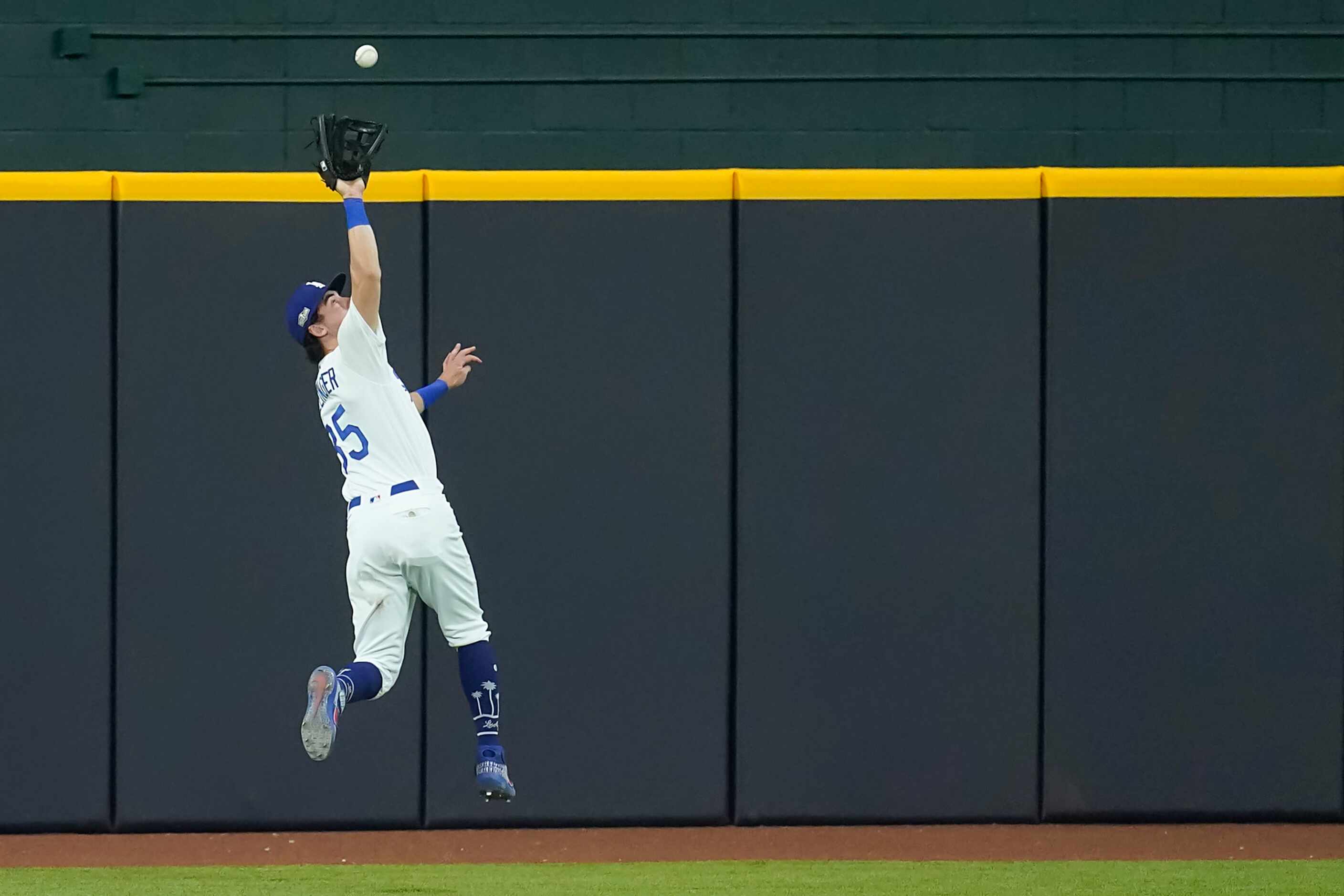 Los Angeles Dodgers center fielder Cody Bellinger makes a leaping catch on a sacrifice fly...