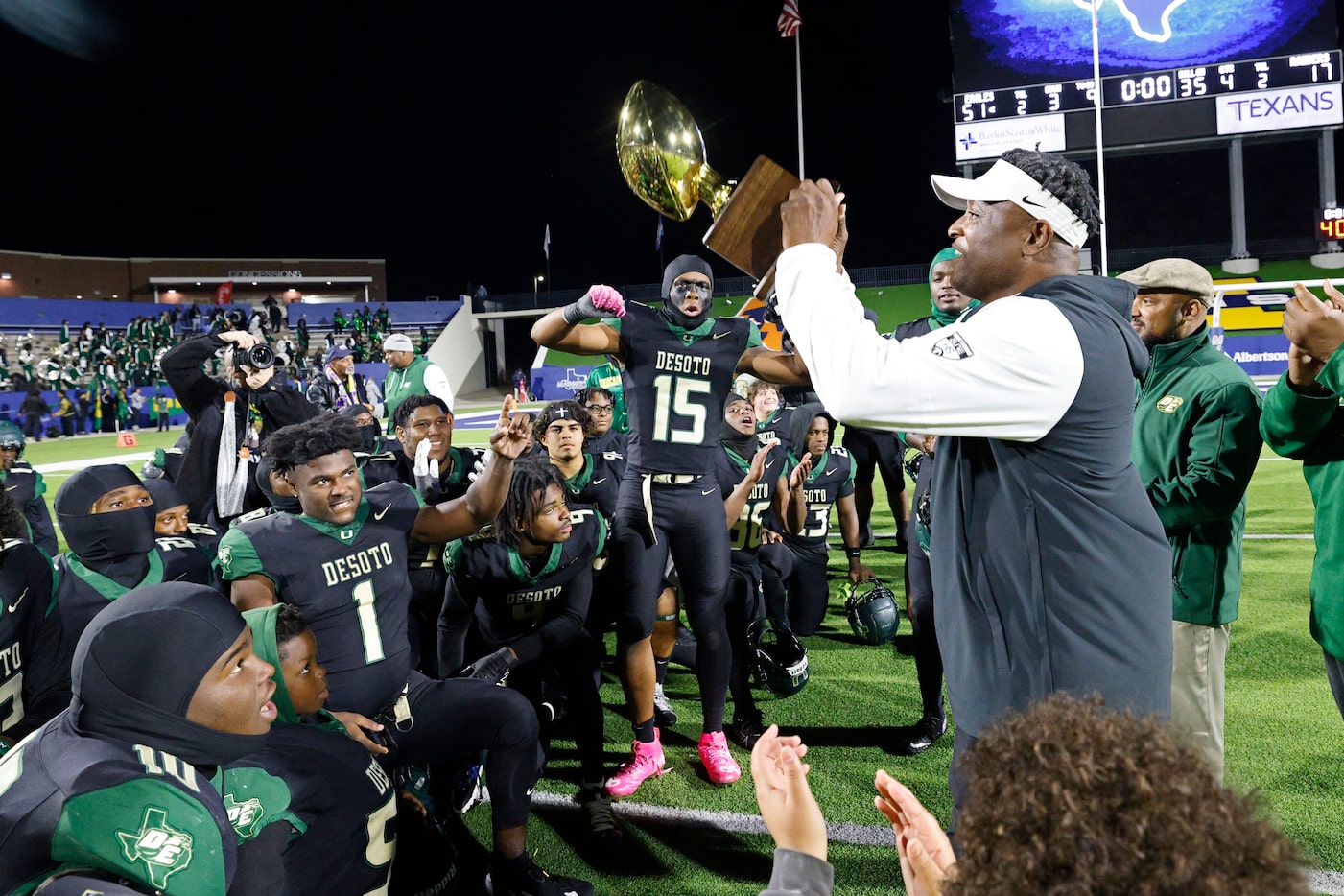 DeSoto's head coach Claude Mathis holds up a trophy after their victory against Wylie East...