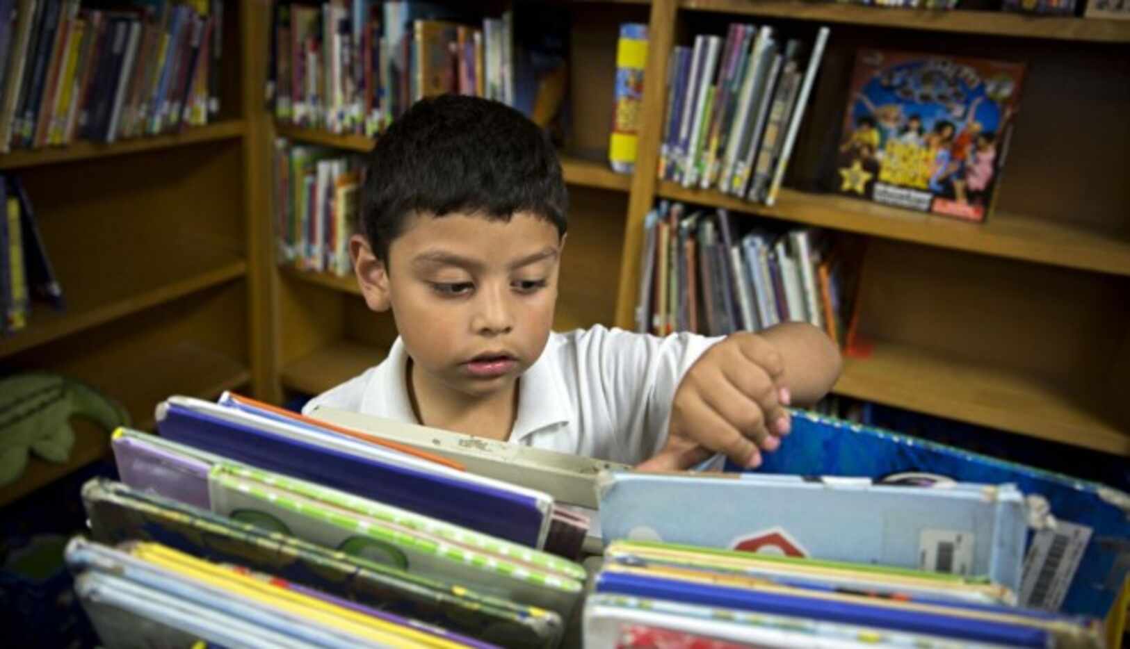 Marcelo Favela, alumno de la primaria Macon de Dallas, hojea libros en la biblioteca de la...