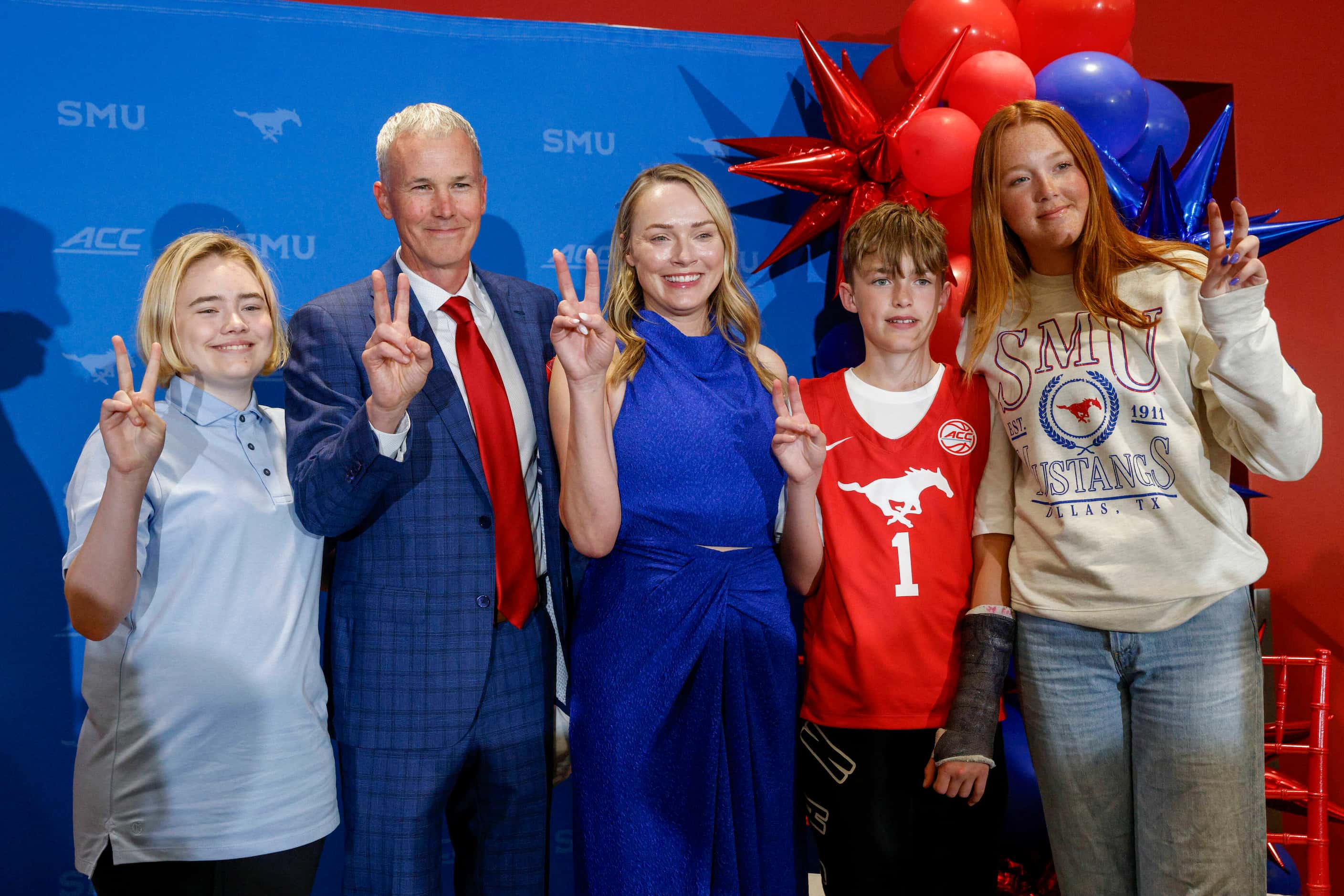 SMU head men's basketball coach Andy Enfield holds up the “Pony Up" sign with his daughter...
