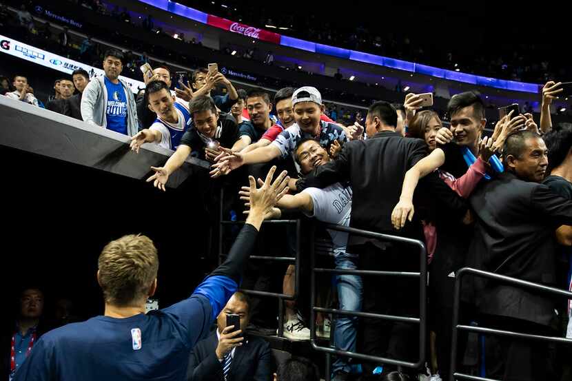 Dallas Mavericks forward Dirk Nowitzki high-fives fans as he leaves the court following an...