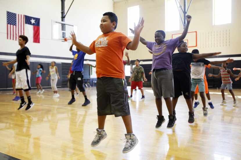 Luis Catalan, 11, does jumping jacks with a group during the Dallas Police Athletic League...
