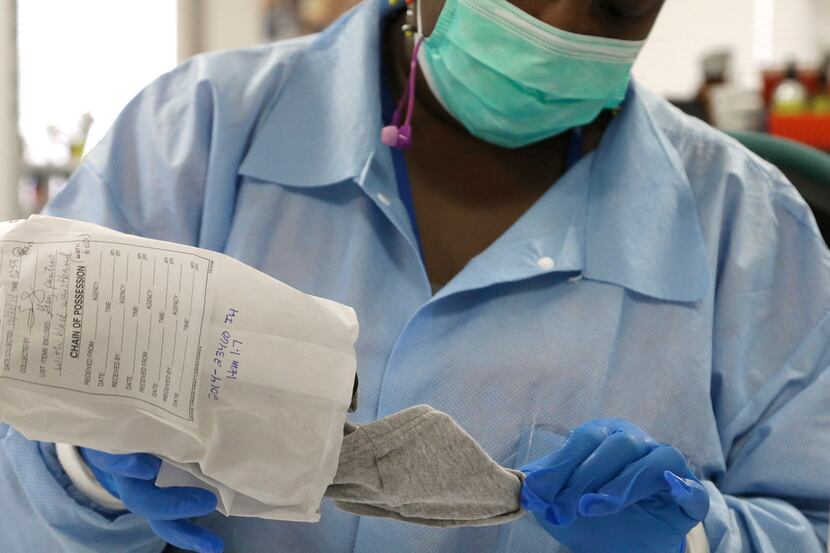 Forensic analyst India Henry removes a pair of underwear from an evidence bag for testing in...