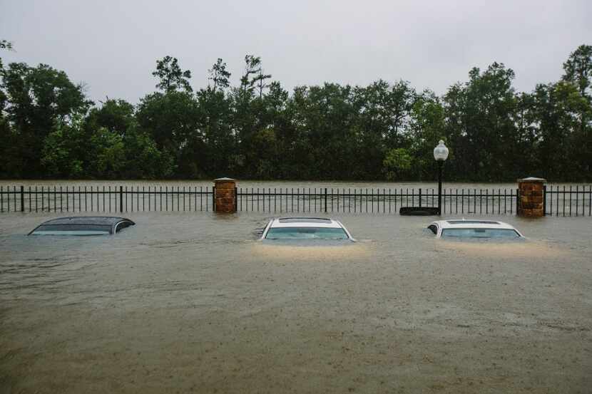 Flooded cars sit in an apartment complex parking lot in Humble on Tuesday. 