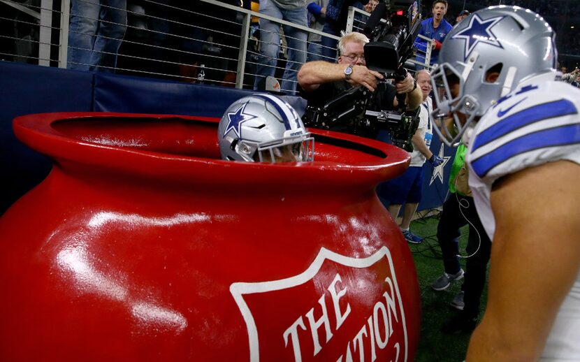 Ezekiel Elliott celebrates after scoring a touchdown by jumping into a Salvation Army red...