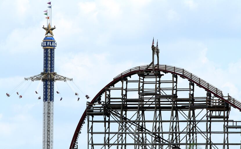 The Texas SkyScreamer whirls riders in the background of the Texas Giant roller coaster on...