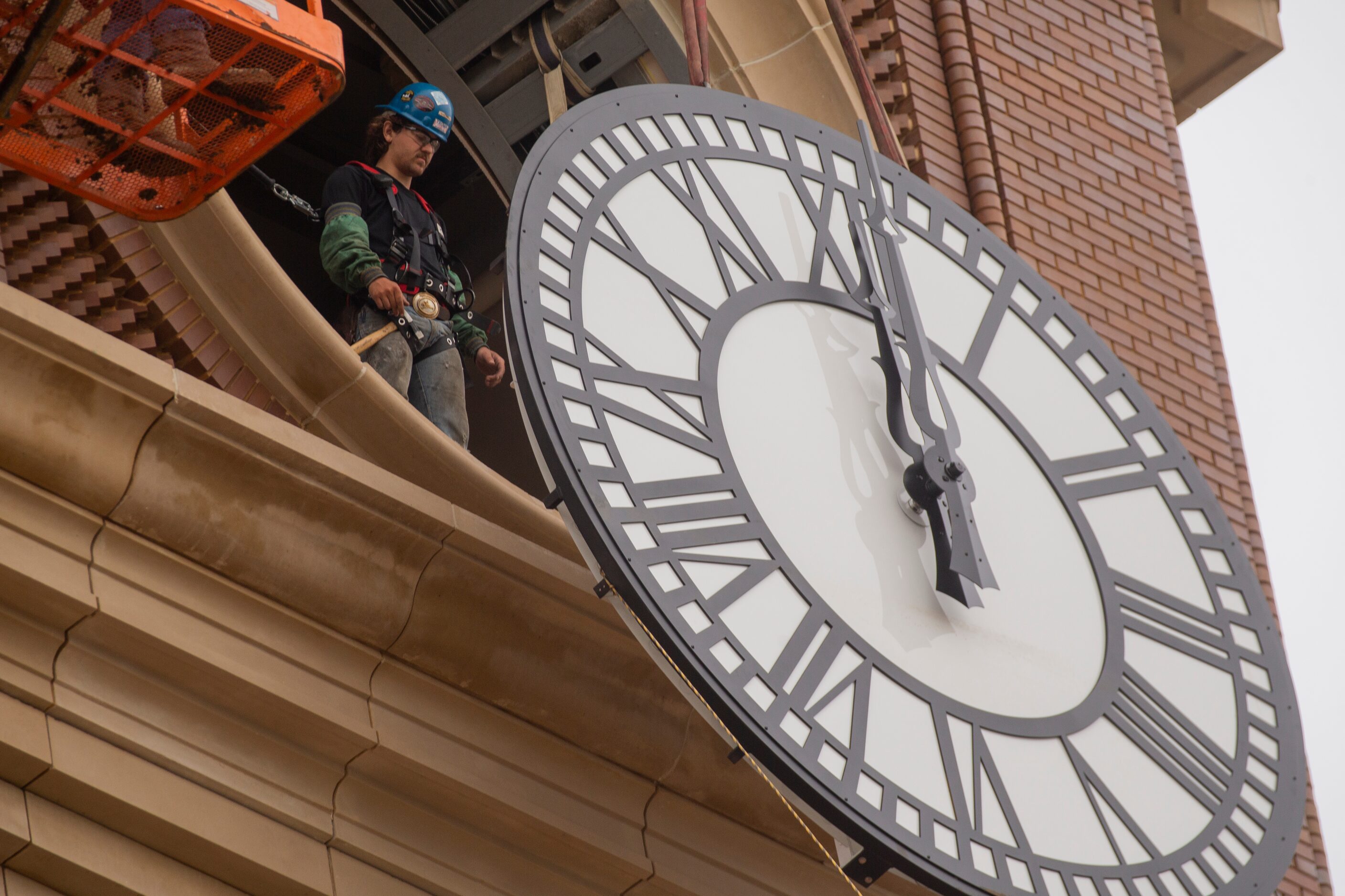 Workers from MEI Rigging & Crating work to install a 12-foot glass clock on the Grapevine...