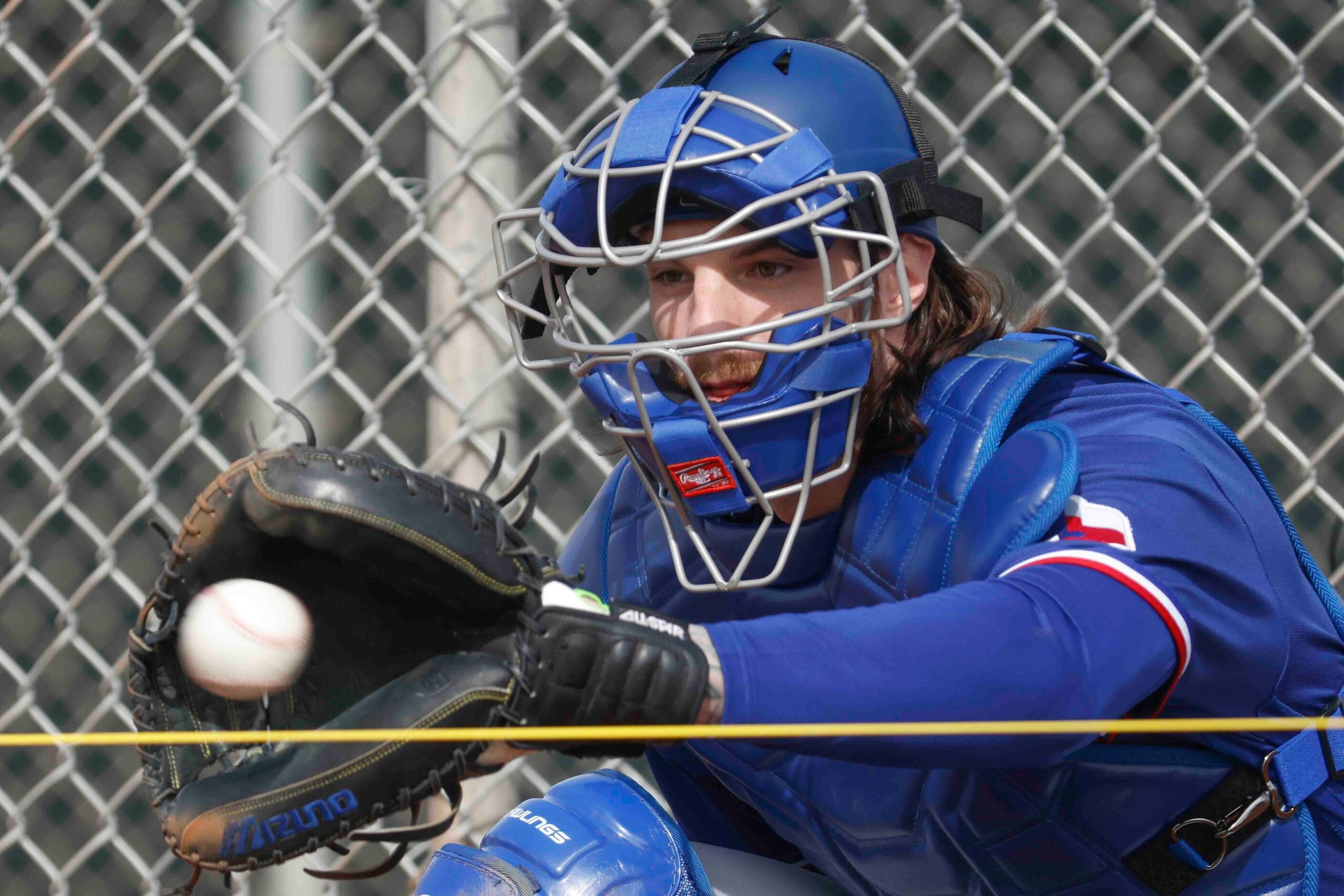 Texas Rangers catcher Jonah Heim catches a ball during spring training workout at the team's...